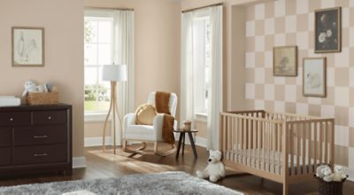 Nursery painted in a checkered pattern with Sand Dollar SW 6099, paintings, rocking chair, 2 large windows, and crib.