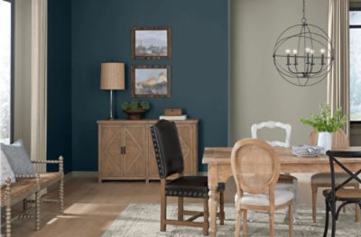 A dining room painted blue with light wood furniture.