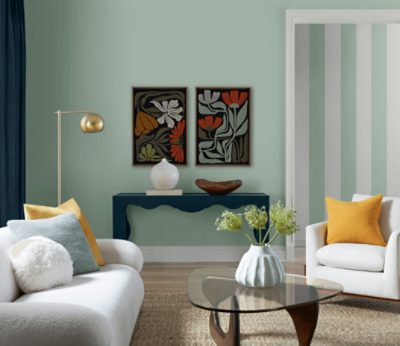 Living room painted in SW 6456 Slow Green with neutral couch, throw pillows, side tables, and decor.