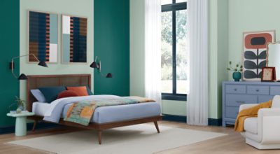 Bedroom painted in SW 6456 Slow Green, large window, bed with lamps on both sides, dresser, and chair.