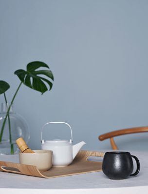 A white tea pot and black mug in front of a wall painted Aleutian SW 6241.