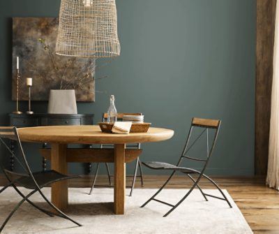 Dining room painted in SW 7622 Homburg Gray with a round wooden table and metal chairs.