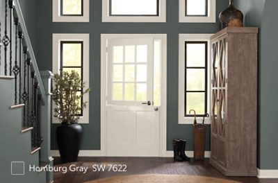 A foyer and staircase painted in SW 7622 Homburg Gray with a white front door.
