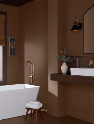 Bathroom walls painted in SW 6089 Grounded with bathtub, sink, wooden stool on the ground with towels on top.