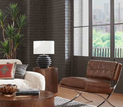 Brick wall painted in SW 7675 Sealskin with windows, brown leather chair, wooden tables, couch.