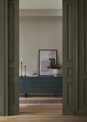 Walls painted in SW 6167 Garden Gate with a dresser with decor on top of it.