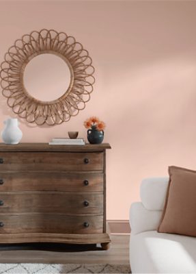 Wall painted in SW 6610, round mirror hung above a wooden dresser with some decor on top.