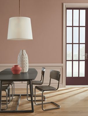 Dining room with a table with vases on it, chairs, a white light and red trim door.