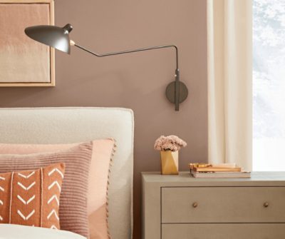 Bedroom with a bed, nightstand and mounted adjustable reading lamp.