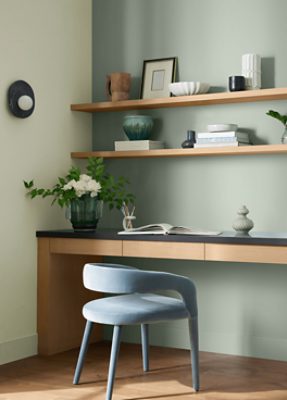 Desk area with shelving with decor on them, a desk and chair, walls painted in SW 6167 Liveable Green.