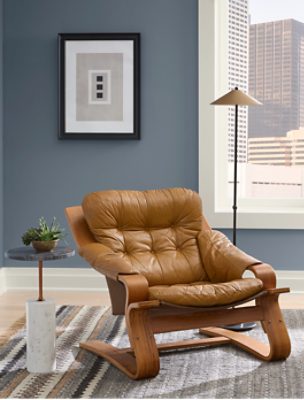 Sitting area with brown leather chair, small side table and lamp with walls painted in SW 6249 Storm Cloud.