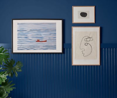 Accent wall with wainscoting painted in SW 6524 Commodore with three art prints.