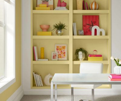 Shelves painted in SW 1667 Icy Lemonade, with bright decor and books, white desk and chair in front of them.