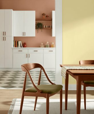 Side of kitchen table and chairs, wall painted in SW 1667 Icy Lemonade, with white cabinets and checkered floor behind it.