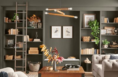 A living room with a wall of built in bookshelves painted Roycroft Bronze Green.