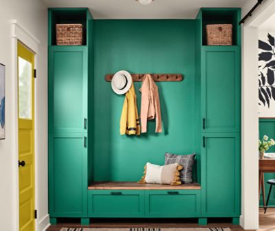 An entryway with built-in shelving, bench and coat hooks painted Alexandrite SW 0060.