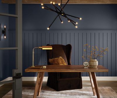 Home office with a wooden desk, golden lamp, a chair and modern chandelier.