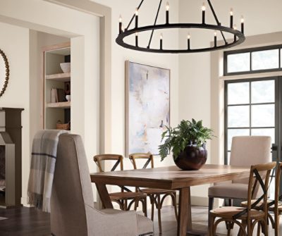Dining room with a table and chairs, large black chandelier and a large wall painting.