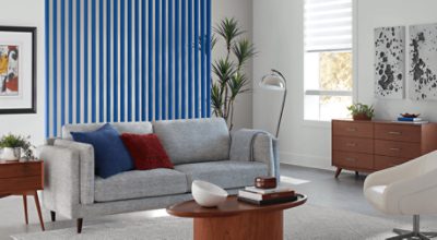 Living room with couch, chair, 2 tables, minimal decor, and vertical slats painted in SW 6967 Frank Blue.