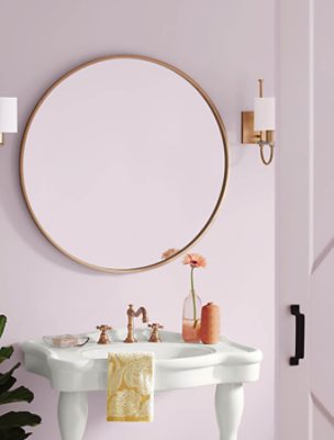 Bathroom with a circular mirror, twin lights and white sink.