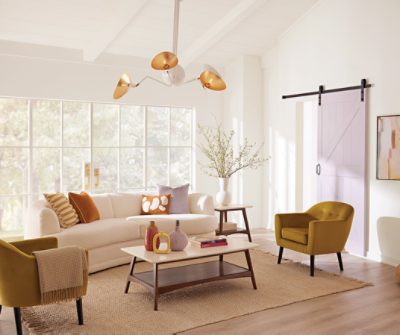 A brightly lit living room with a large window, couch and twin chairs and coffee table.