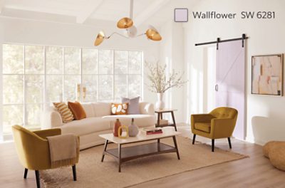 A brightly lit living room with a large window, couch and twin chairs and coffee table.