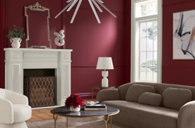 Living room painted in SW 7578 Borscht, brown couch, white fireplace, window, minimal decor.
