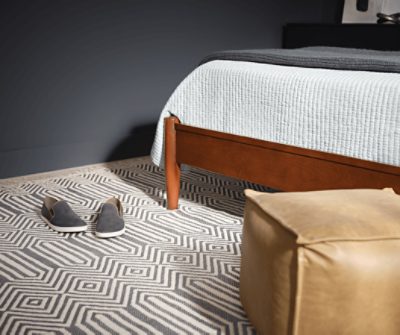 A bedroom with a geometric rug and SW 7076 Cyberspace painted walls.