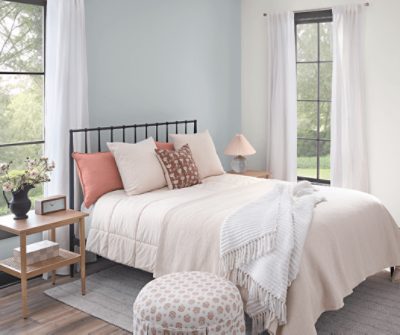 Bedroom with a bed with pillows, black frame, nightstand, large windows and walls painted in SW 6233 Samovar Silver.