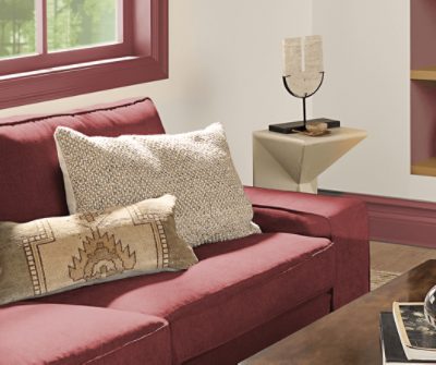 A maroon couch with pillows next to a side table.