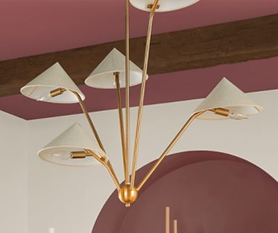 A gold accented chandelier hanging from a maroon painted ceiling with wood beams.