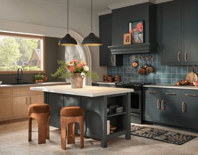 Kitchen cabinets painted in SW 7062 Rock Bottom with gold hardware and glossy dark blue backsplash with pots hanging on it, island and barstools.
