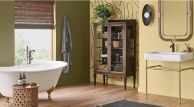 Bathroom painted in Palm Leaf SW 7735 on one wall and another in a yellow tone, footed tub, glass dresser, and sink.