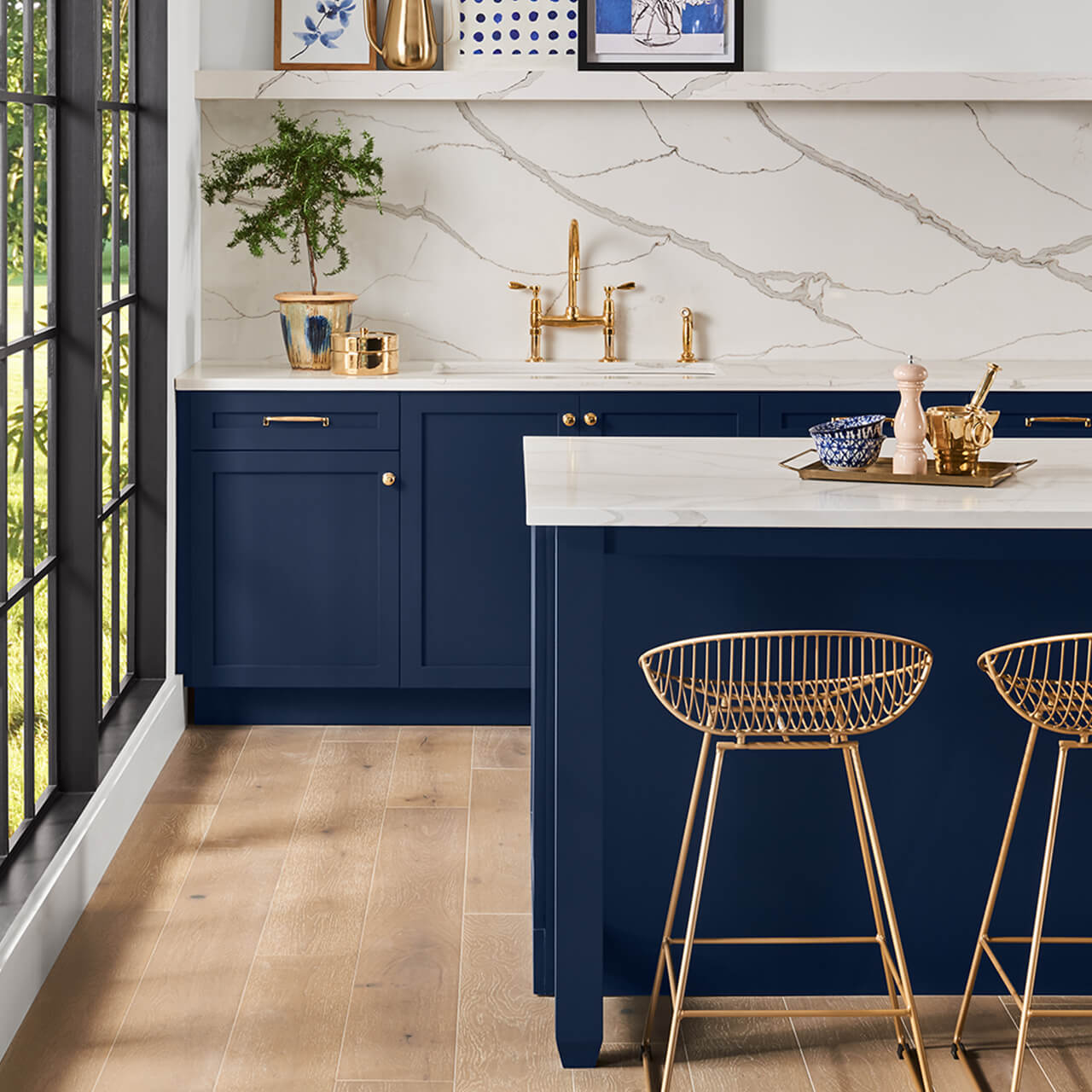 A contemporary kitchen with white countertops, marble backsplash and navy blue cabinets. S-W featured color: SW 6244 Naval.