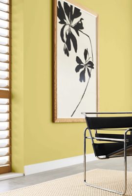 Room painted Sherwin-Williams Chartreuse SW0073 with a large picture of a black flower alongside a black leather chair. 