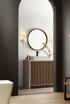 Bathroom painted Sherwin-Williams Clove SW9605 with an arched doorway paired with a wooden vanity and round mirror.