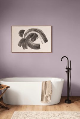 Bathroom painted Sherwin-Williams Mauve Finery SW6282 with a white bathtub and light wooden floors.