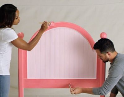 A couple painting a headboard pink