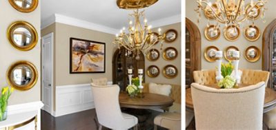 Opulent but cozy dining room with round table and tufted upholstered chairs, gold-framed mirror plate wall decor, neutral walls with white wainscoting, and gold chandelier.