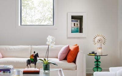 A modern sitting room in designer Seth Van Den Bergh’s studio with white furniture and colorful accents, including books, a sculpture, and an orchid on a glass table, painted Westhighland White by Sherwin-Williams.