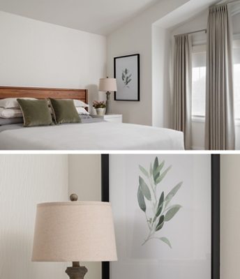 A modern bedroom with a wooden bed, white and gray bedding, green pillows, a white nightstand with a lamp, and botanical artwork.