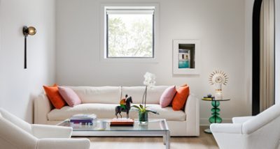 A modern sitting room in designer Seth Van Den Bergh’s studio with white furniture and colorful accents, including books, a sculpture, and an orchid on a glass table, painted Westhighland White by Sherwin-Williams.