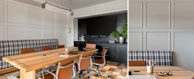 A modern conference room with a large wood table, leather chairs, plaid bench, and mounted TV on a paneled wall.