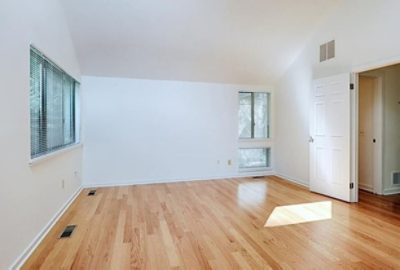 large open room with hardwood floors and white walls.