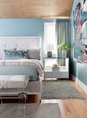 blue walled bedroom with matching decor and natural light.