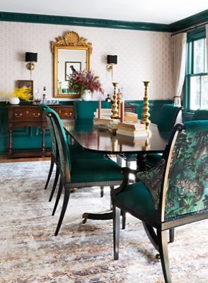 Image of dining room with dark green accents and patterned wallpaper.
