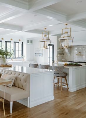 Very bright white and neutral kitchen with wooden floors and many windows.