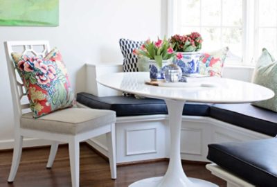 Image of bright white kitchen nook with seating and decorative pillows.
