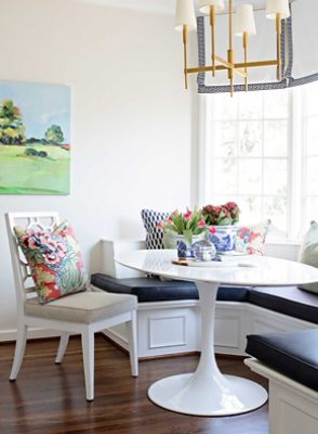  Image of bright white kitchen nook with seating and decorative pillows.