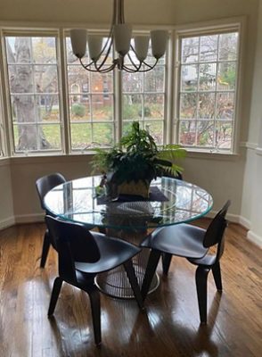 before photo of clear kitchen table and dark chairs near windows.